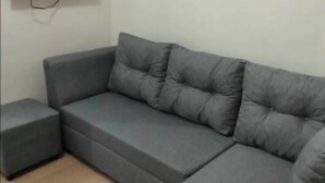Ein graues Ecksofa mit passendem Hocker und Holzboden.