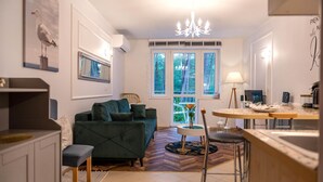 A modern living room with a green sofa, a dining area with a round table, and a kitchen with a sink and stove. - Apartment in Pobierowo Near Baltic Beach (Rewal)