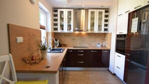 Une cuisine moderne avec des meubles de couleur sombre, un réfrigérateur en acier inoxydable et un plan de travail en bois.