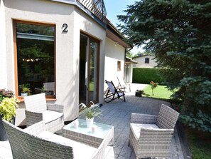 A modern house with a patio area featuring wicker furniture and a glass table. - Holiday Home in Kopalino Near Sandy Beach (Choczewo)
