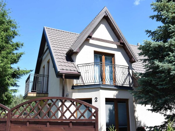 A two-story house with a balcony, a wooden gate, and a number '2' on the facade. - Holiday Home in Kopalino Near Sandy Beach (Choczewo)