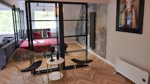 Ein modernes Zimmer mit einem Bett, zwei Stühlen, einem kleinen Tisch und einer Heizung.