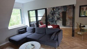 Ein modernes Wohnzimmer mit einem Ecksofa, einem runden Couchtisch und einem großen Fenster.