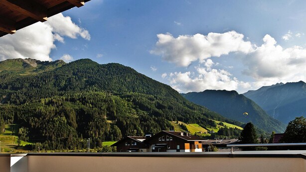 A mountain landscape with a view of a building with multiple windows and a sloped roof.