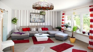 Ein modernes Wohnzimmer mit einer Eckcouch, einem Glastisch und roten und weißen Streifenstoren.