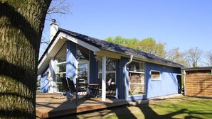 Ein blaues Haus mit Terrasse, großen Fenstern und Schornstein.