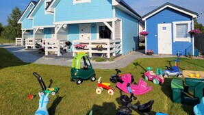 A blue house with a porch, a garage, and a small attached building. - Holiday Home in Niechorze Near Lighthouse (Rewal)