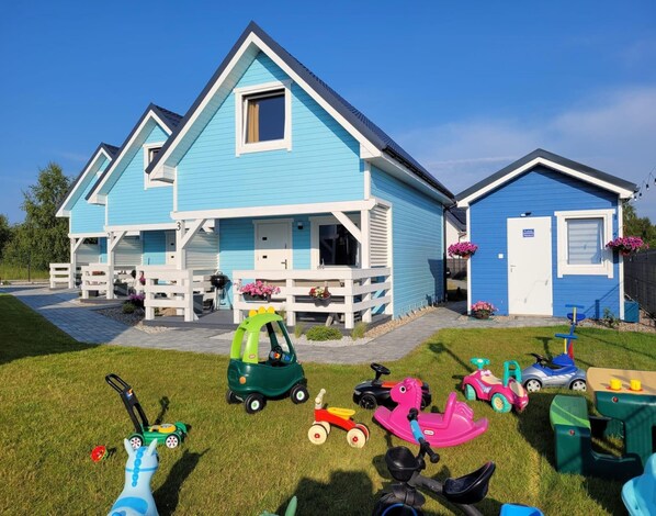 A blue house with a porch, a garage, and a small attached building. - Holiday Home in Niechorze Near Lighthouse (Rewal)