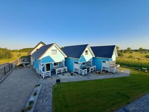 A row of three light blue houses with dark roofs, each with a porch and a small garden area. - Holiday Home in Niechorze Near Lighthouse (Rewal)