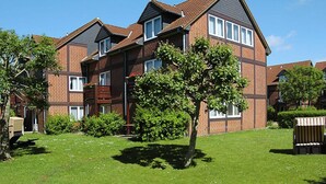 A two-story brick apartment building with multiple windows and a sloped roof. - Appartementhaus auf Pellworm (Pellworm)