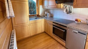 Una cocina compacta con armarios de madera, horno empotrado y lavavajillas.