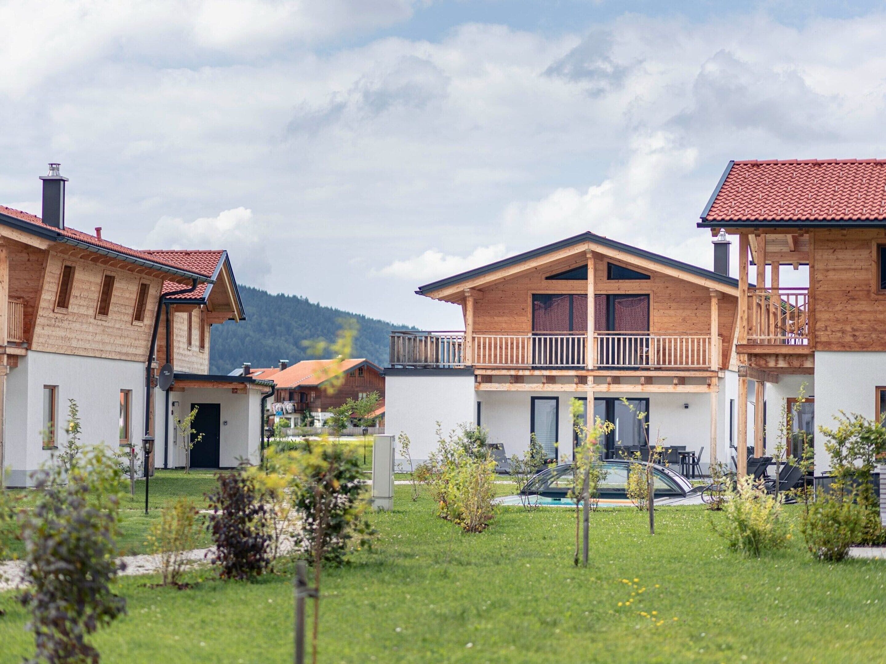 Un quartier résidentiel avec des maisons en bois, une piscine et un paysage montagneux en arrière-plan.