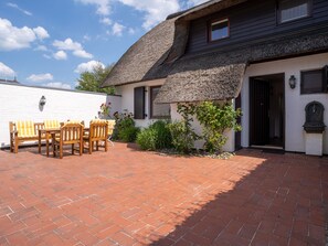 A house with a thatched roof, a brick patio, and a white exterior wall. - Thatched Roof House in St.peter Ording (St. Peter-Ording)