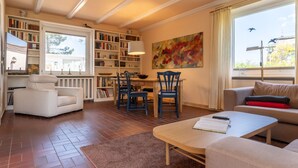 A spacious living room with a fireplace, a dining area, and a large bookshelf. - Thatched Roof House in St.peter Ording (St. Peter-Ording)