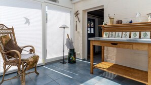 A room with a wicker chair, a table with botanical illustrations, and a skylight. - Thatched Roof House in St.peter Ording (St. Peter-Ording)