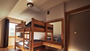 Une chambre avec un lit superposé, un bureau et un banc en bois, une fenêtre avec des rideaux et une porte.