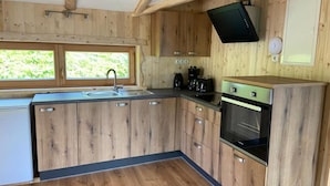 A compact kitchen with wooden cabinets, a built-in oven, a sink, and a window providing natural light. - Chalet in Zillertal Near Hochzillertal Ski Area (Zellberg)
