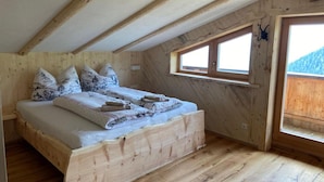 A wooden bedroom with a bed, pillows, and a window. - Chalet in Zillertal Near Hochzillertal Ski Area (Zellberg)