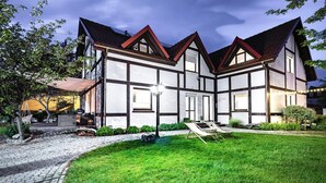 Une maison traditionnelle à colombages, dotée d’une pelouse bien entretenue et d’une allée pavée.