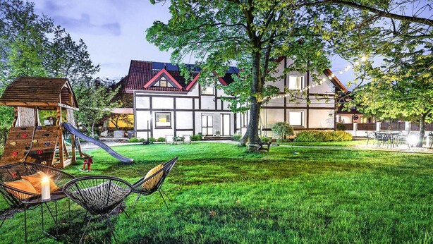 Une maison avec un grand jardin, un espace de jeux et un coin repas.