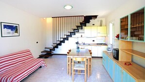 Un espace de vie compact comprenant une kitchenette, un coin repas et un escalier menant à un niveau supérieur.