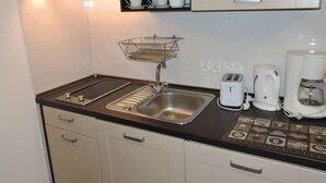 A small kitchenette with a sink, a coffee maker, a toaster, and a bread box. - Kolczewo Cottage With BBQ & Garden (gmina Wolin)