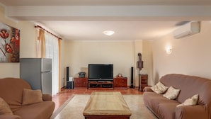 Una sala de estar con un sofá, una mesa de centro, un televisor y un aparador.
