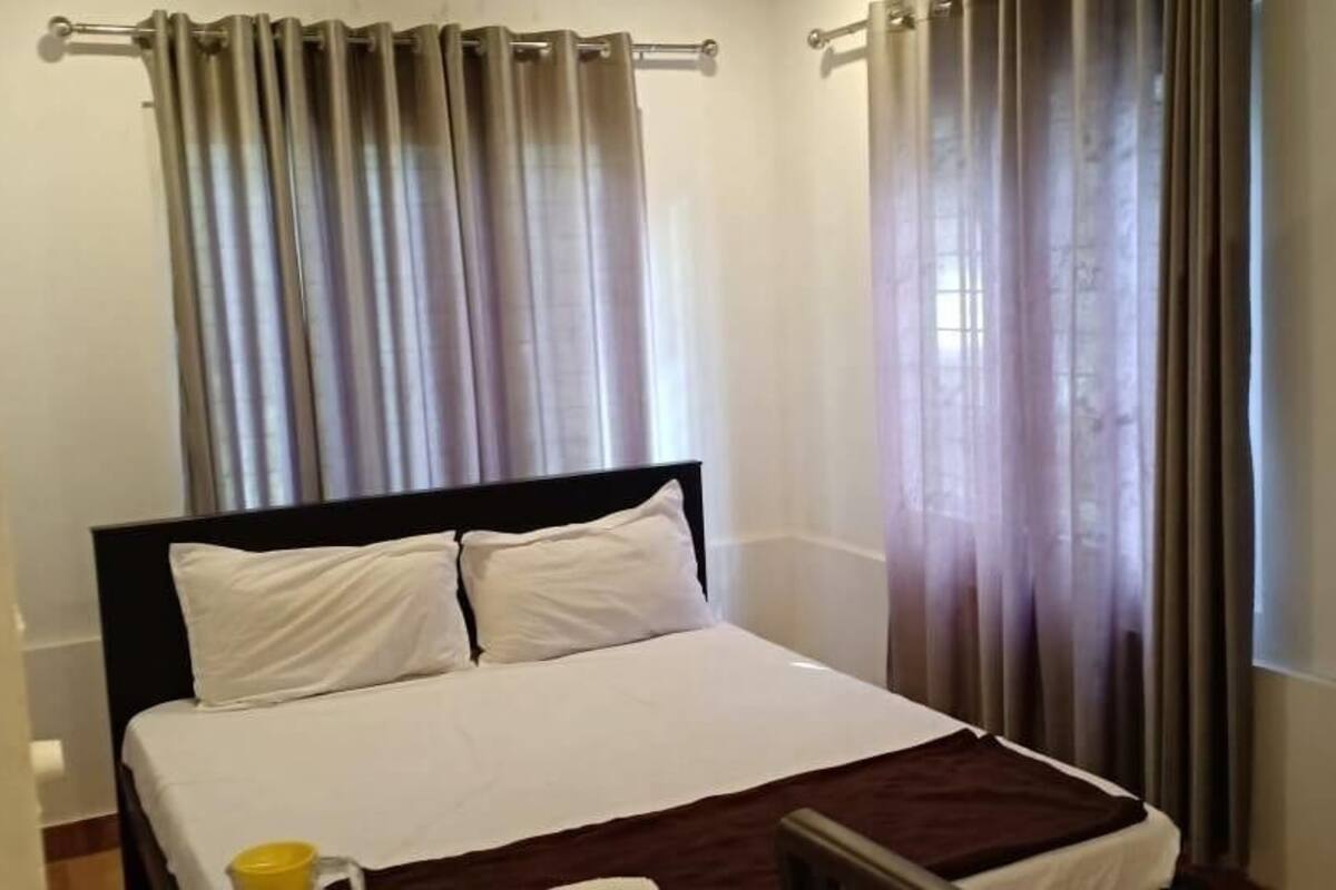 A hotel room with a bed, curtains, and a wooden door.