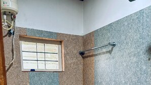 Un baño pequeño con inodoro, ventana y zona de ducha.