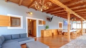 A spacious living area with a wooden ceiling, a large sofa, a dining table with chairs, and a kitchen area. - Pool Fun House Betiga 1 With gym (Vodnjan)