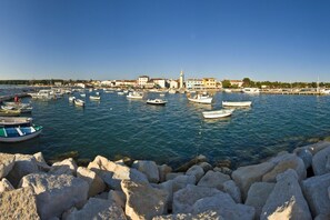 A harbor with boats docked, a prominent church, and a rocky shoreline. - Pool Fun House Betiga 1 With gym (Vodnjan)