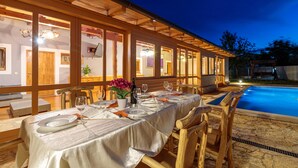 A dining area with a table set for four, a poolside view, and a wooden exterior. - Pool Fun House Betiga 1 With gym (Vodnjan)