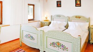A bedroom with two beds, wooden flooring, a chandelier, and floral bed headboards. - Farmhouse in Kossen Near Kitzbuhel Alps (Koessen)