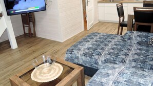 Ein gemütlicher Wohnbereich mit Fernseher, Esstisch und Küchenzeile.