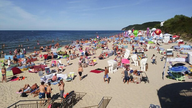 Ein überfüllter Strand mit vielen Sonnenschirmen und Liegestühlen, der ein beliebtes Reiseziel kennzeichnet.