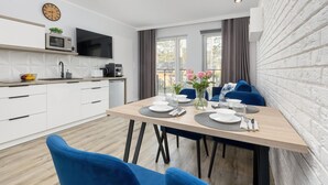 A modern kitchen with white cabinets, a microwave, and a flat-screen TV. - Comfortable Apartment, Pool, Close to the Beach (Rewal)