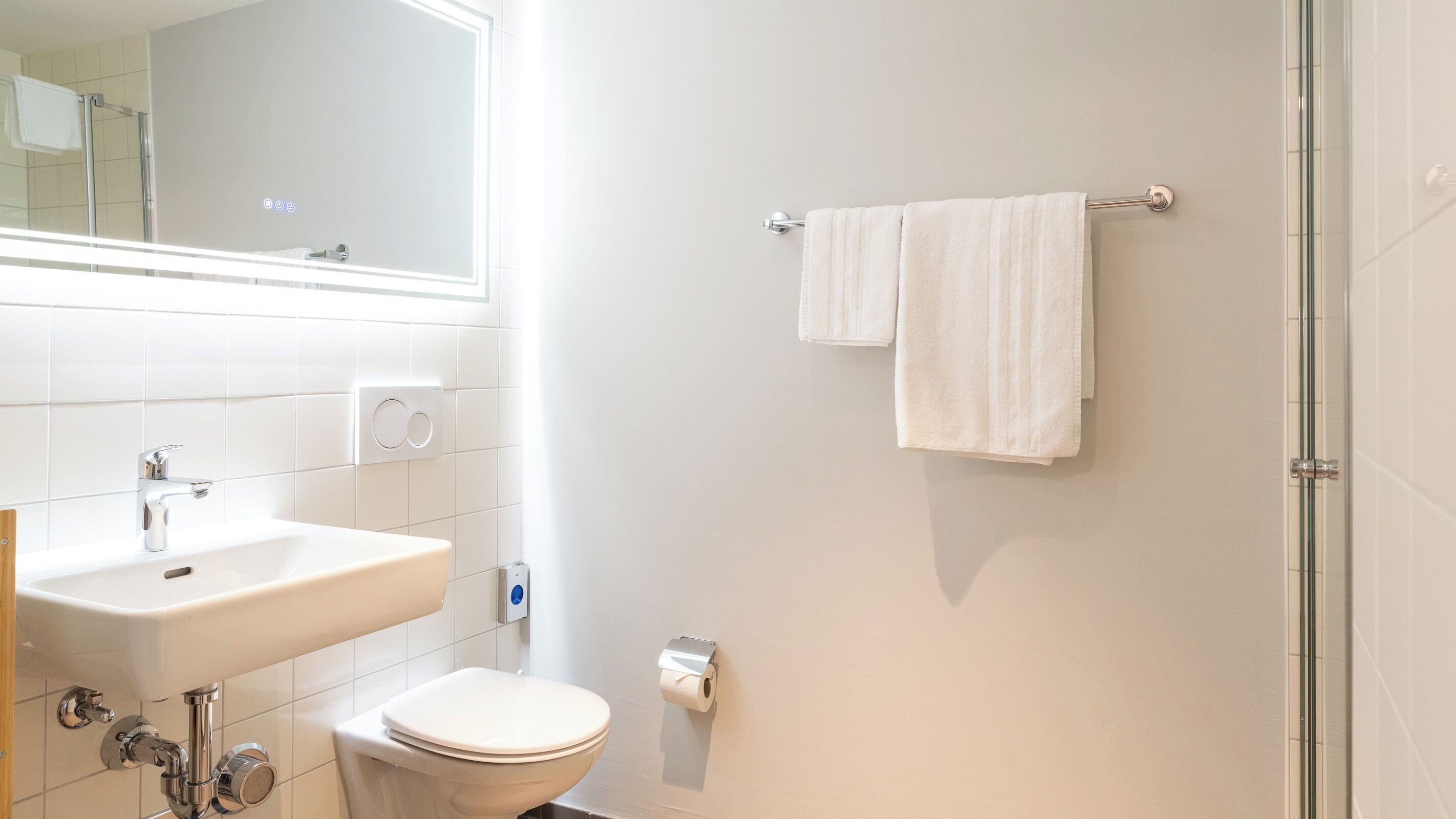 A bathroom with a sink, toilet, and a towel rack.