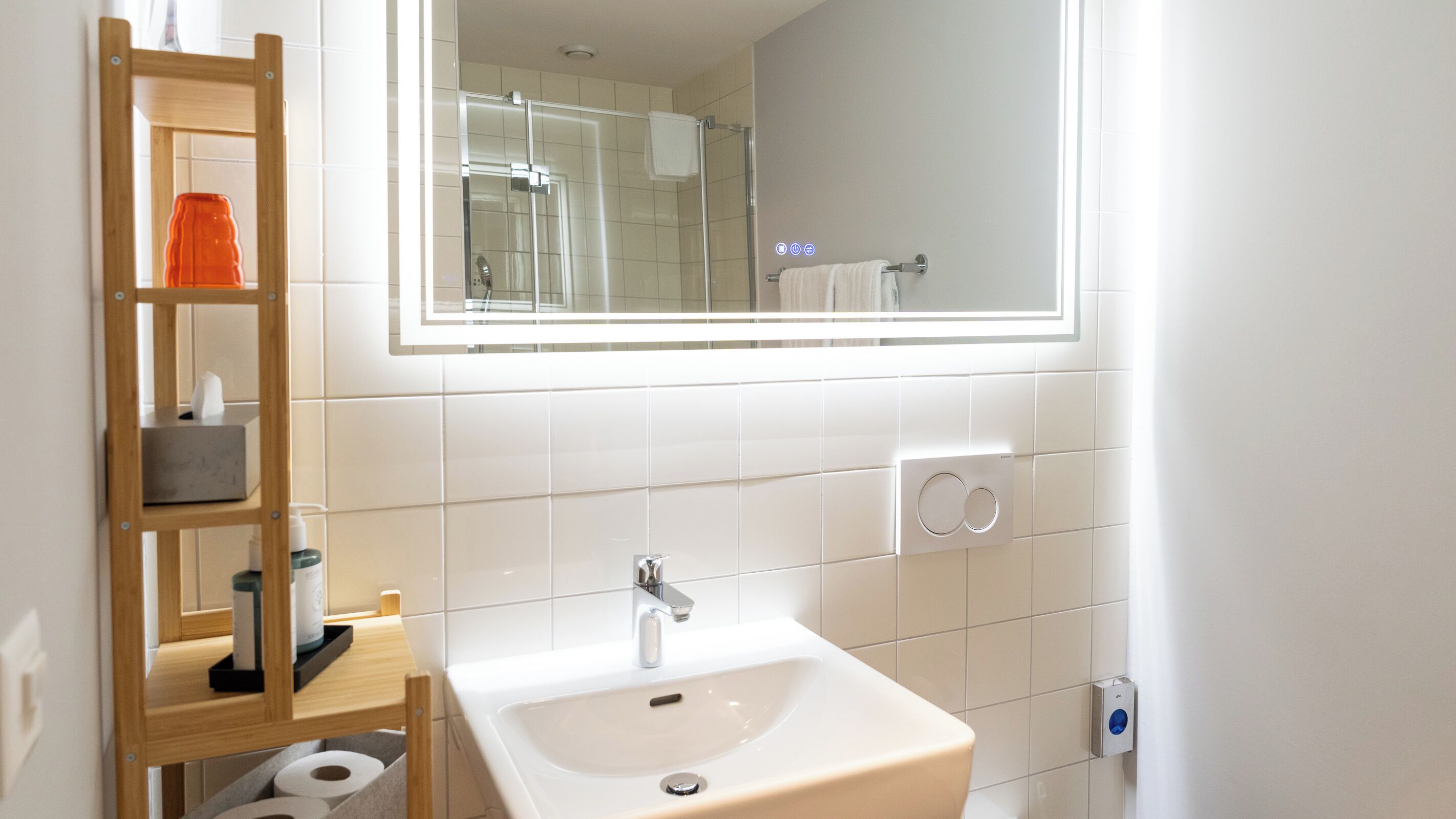 Ein Badezimmer mit Waschbecken, Spiegel und einem Holzboden mit Pflegeprodukten.