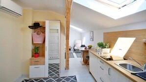 Eine kleine Küche mit Oberlicht, Holzschränken und einer Essecke.