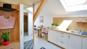 Eine kleine Küche mit Oberlicht, Holzbalken und einer Essecke mit Tisch und Stühlen.
