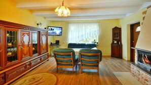 A living room with a wooden cabinet, a television, a fireplace, and a sofa. - Spacious Cottage, Idyllic Right on the Lake, Spore (Szczecinek)