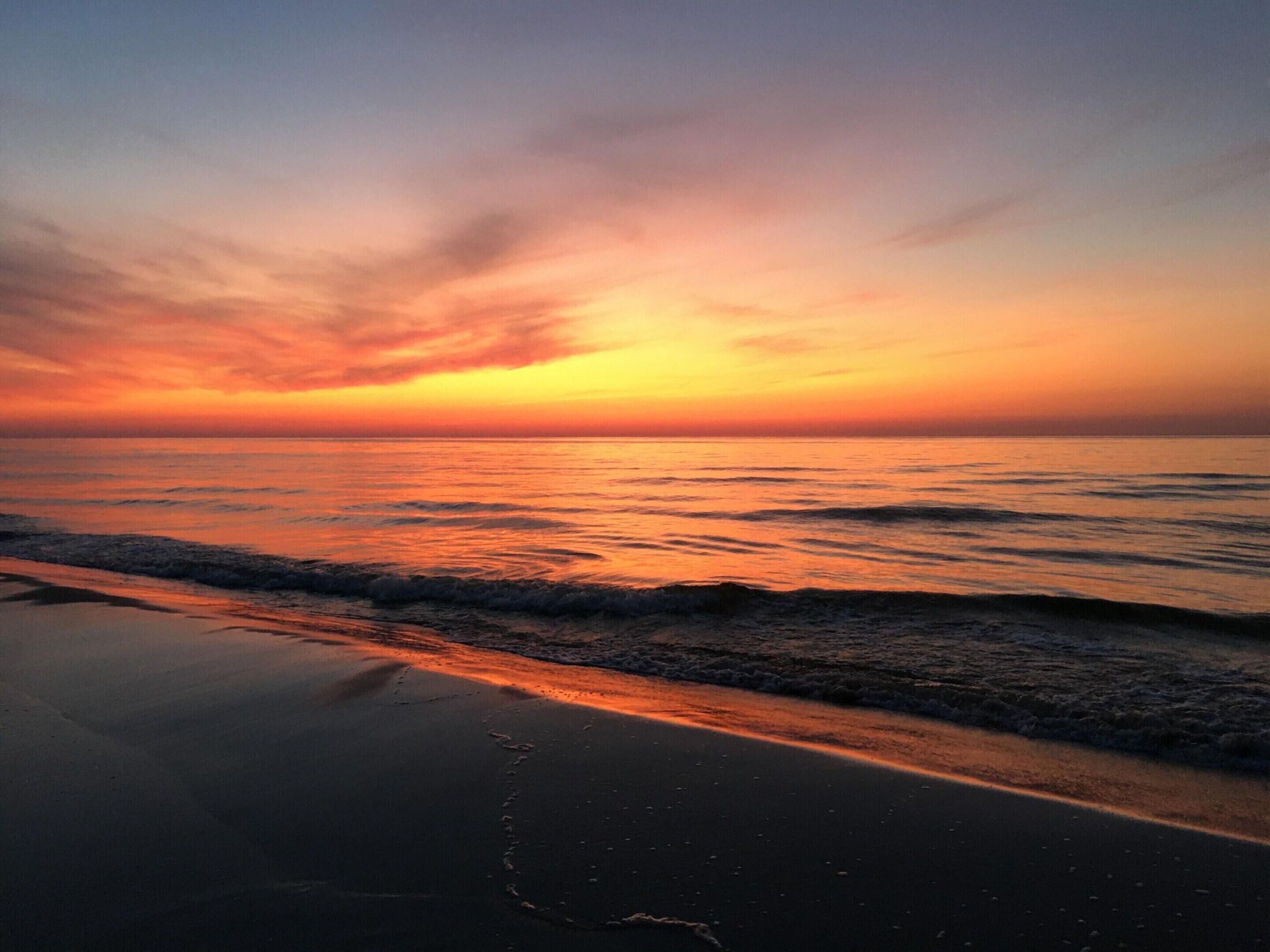 A beach at sunset with waves gently lapping the shore.