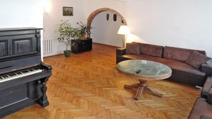 A living room with a grand piano, a round coffee table, a brown leather sofa, and a potted plant. - Holiday Appartment in Stepnica for 4 Persons (Stepnica)