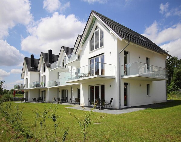 A modern two-story house with a balcony, a patio area, and a well-maintained lawn. - Appartement Hafenflair am Plauer See (Plau am See)