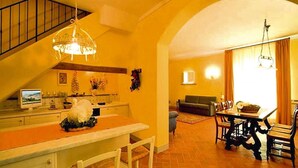A kitchen with a dining area, featuring a staircase, a chandelier, and a television. - Apartment in Tuscany With Golf & Pools (Gambassi Terme)