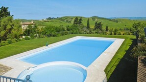 A rectangular swimming pool with a circular hot tub, surrounded by a well-maintained lawn and a wooden deck. - Apartment in Tuscany With Golf & Pools (Gambassi Terme)