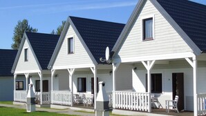 A row of white cabins with dark roofs, each featuring a porch and outdoor seating. - Holiday Home Ustronie Morskie Near Beach (Ustronie Morskie)