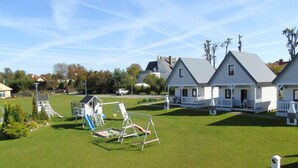 A residential area with a well-maintained lawn, a playground, and white houses with grey roofs. - Holiday Home Ustronie Morskie Near Beach (Ustronie Morskie)