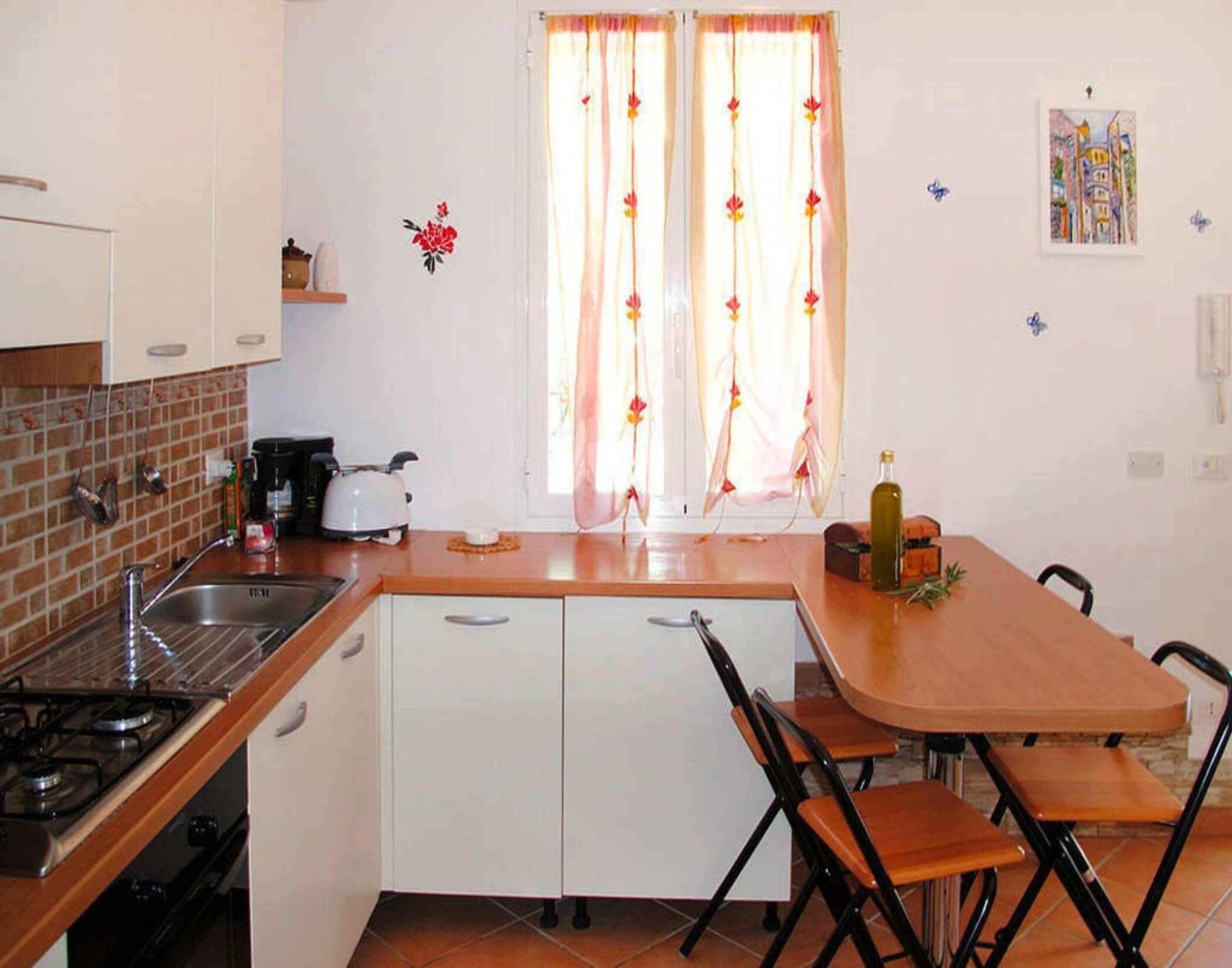 Une cuisine compacte équipée d’une cuisinière à gaz, d’un évier et d’un coin repas avec une table et des chaises.
