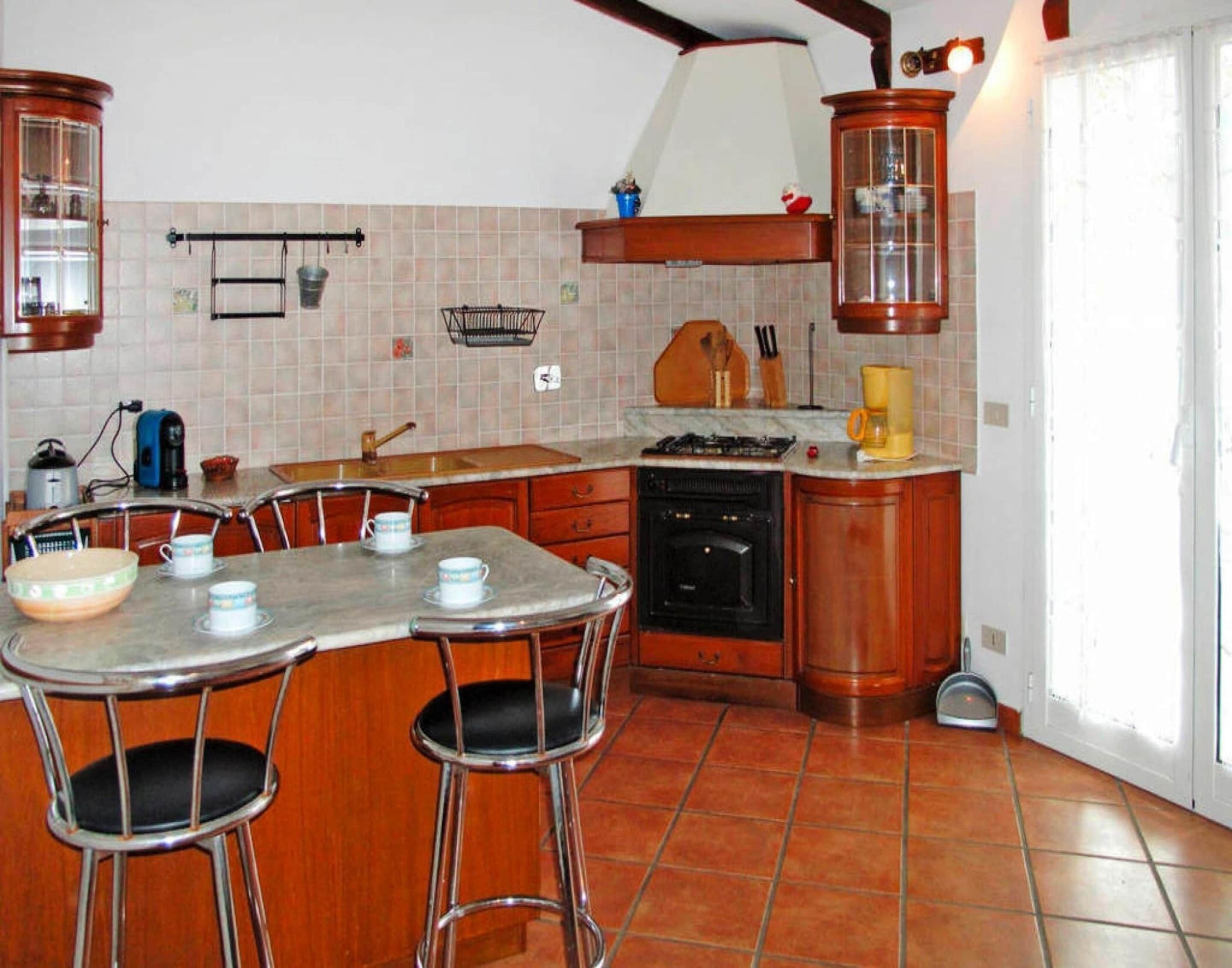 A kitchen with a dining table, chairs, a stove, and cabinets.